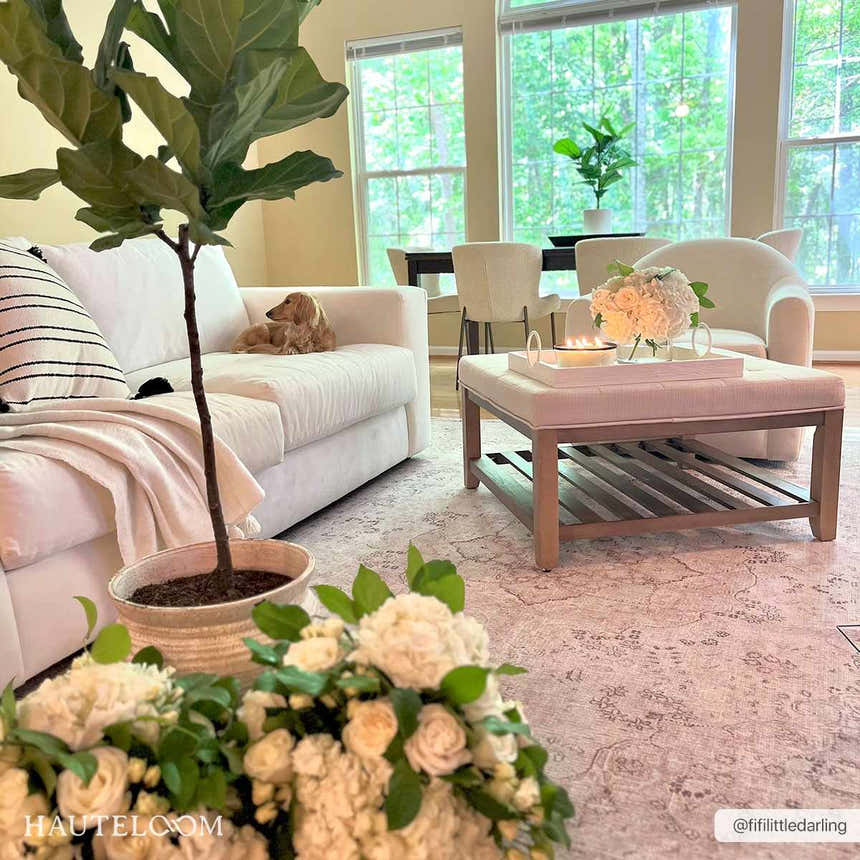 Bright living room with a white sofa, ottoman, and Bethany Vintage Flat Pile Washable Rug in beige and blush tones. Roomscene-Rectangle