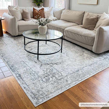 Living room scene with a beige sectional sofa and Hera Olive Boutique Washable Rug under a glass coffee table. Roomscene-Rectangle