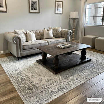 Living room with a cloud gray Rudoblu Boutique Washable Rug, tufted sofa, and dark wood coffee table. Roomscene-Rectangle