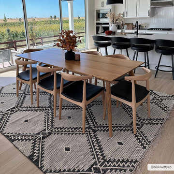 Dining room with a Brownhills hand woven rug, wood table, black chairs, and a view of a field. Cream and black rug. Roomscene-Rectangle