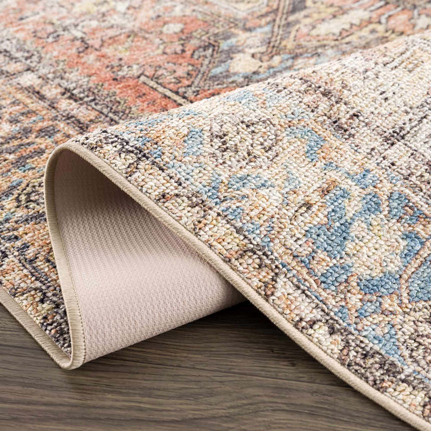 Close-up of Beck Peach Washable Area Rug showing the traditional pattern, beige backing, and soft texture. Fold