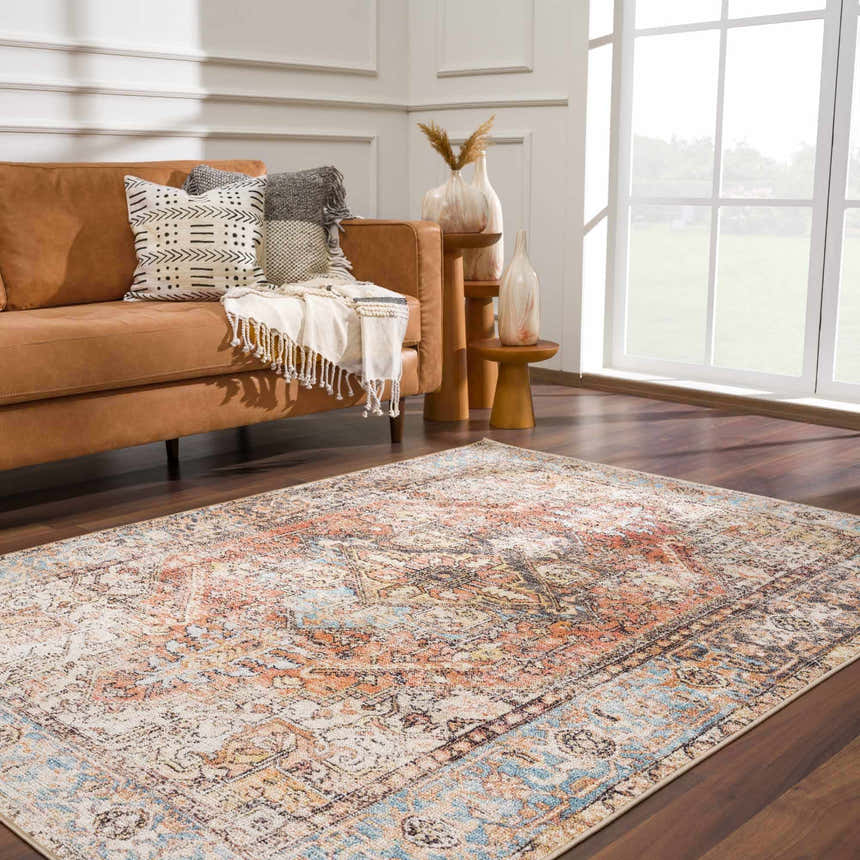 Living room scene with a Beck Peach Washable Area Rug, brown leather sofa, decorative pillows, and wood accents. Roomscene-Rectangle