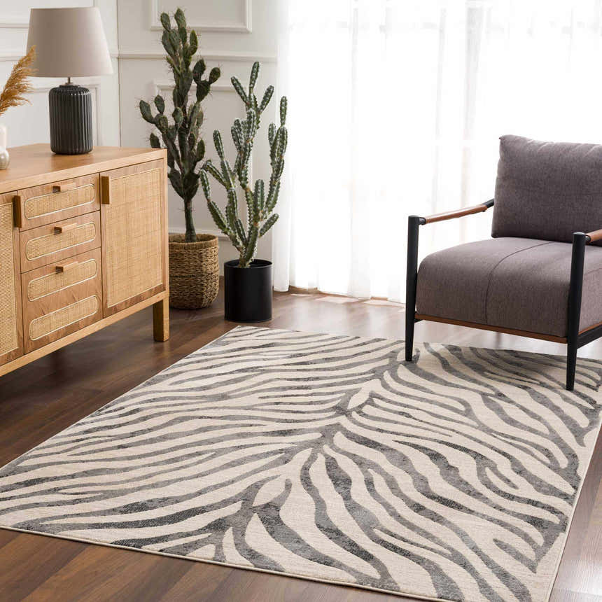 Living room scene with a Gray Ecorse Zebra Print Area Rug, wood cabinet, cactus plants, and gray armchair. Roomscene-Rectangle