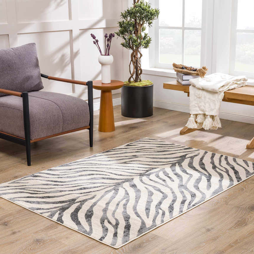 Living room scene with a Gray Ecorse Zebra Print Area Rug, gray chair, wood accents, and natural light. Roomscene-Rectangle
