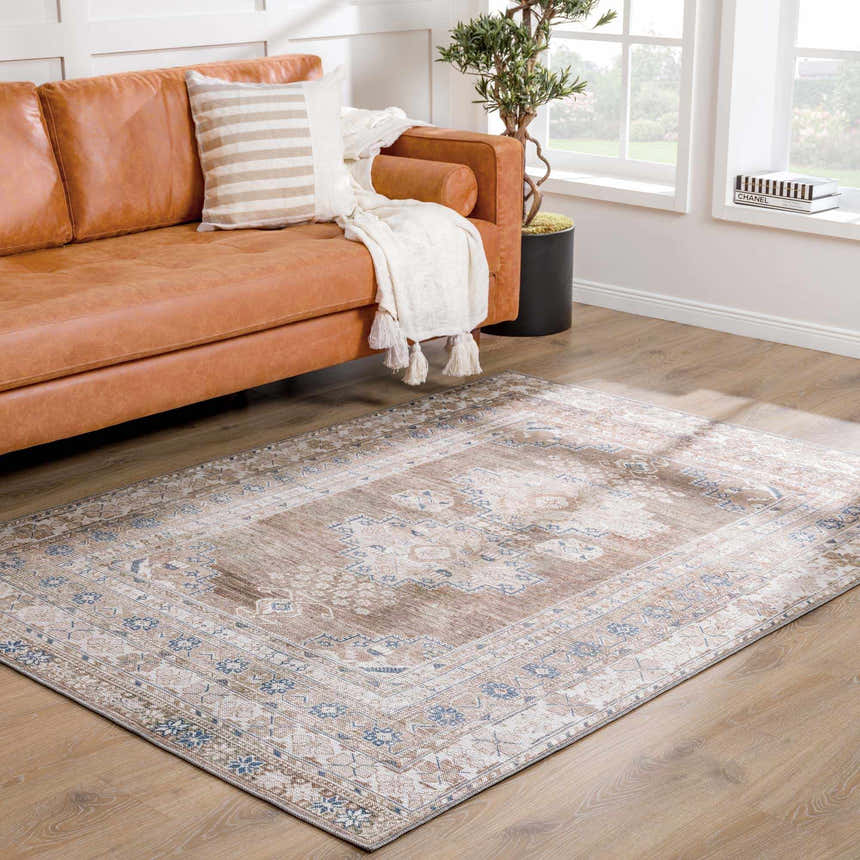Living room scene with a Baltinglass Flat Pile Washable Rug in blue, cream, and beige under a caramel leather sofa. Roomscene-Rectangle