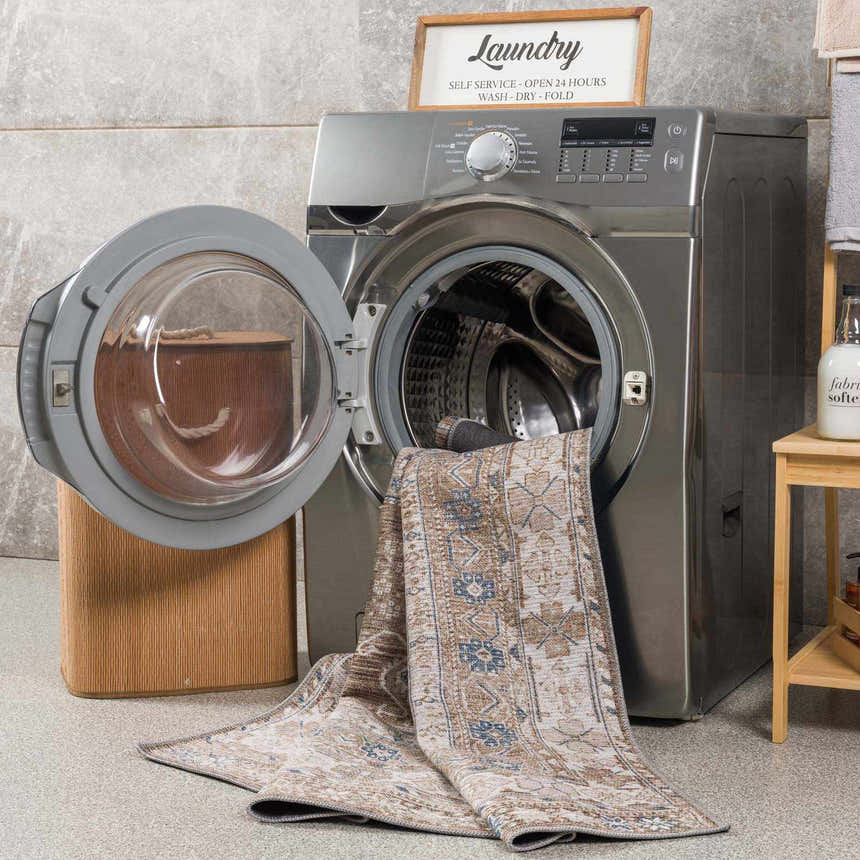 Baltinglass Flat Pile Washable Rug in a laundry room. Rug is beige, blue, and brown with a traditional pattern. Washing-Machine