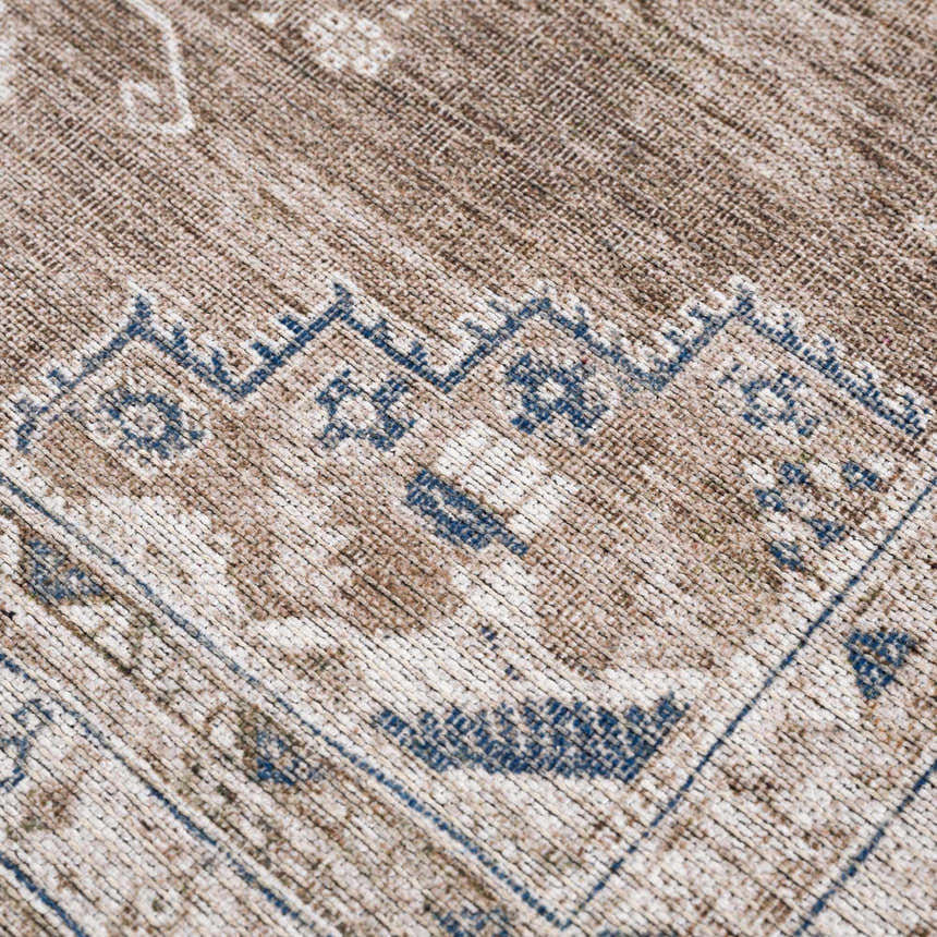 Close-up of the Baltinglass Washable Rug. Beige and brown rug with a traditional blue and cream pattern. Texture