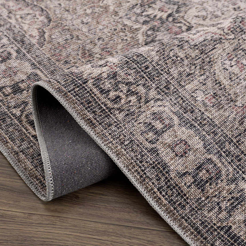 Close-up of the Greenpoint Dusty Blue Washable Rug. Beige, black, and red oriental pattern with a chenille-polyester texture. Fold
