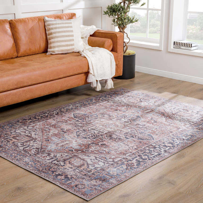 Living room scene with Viho Vintage Flat Pile Washable Rug in brown, blue, and peach tones under a leather sofa. Roomscene-Rectangle