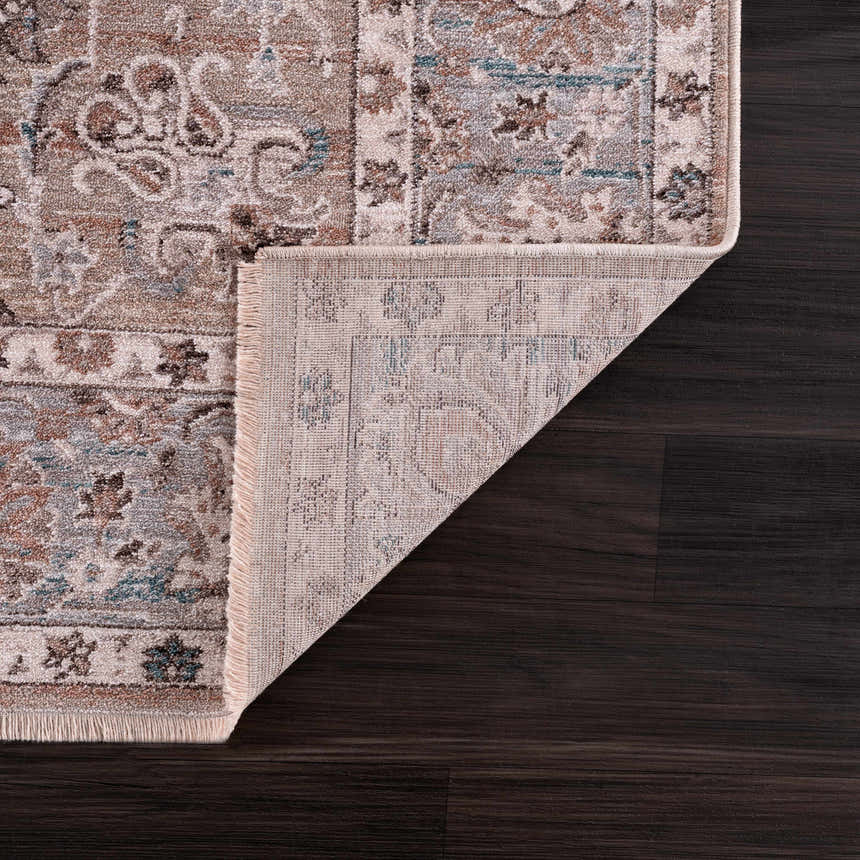 Close-up of the Civankan Area Rug showing the traditional pattern, brick red, denim, and brown colors, and rug backing. Fold