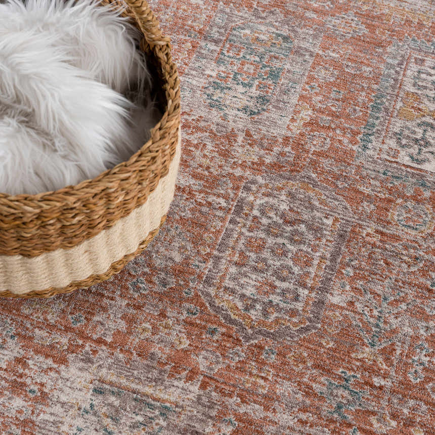 Close-up of the Casta Area Rug in beachhouse colors with a traditional, faded design and a woven basket. Styleshot