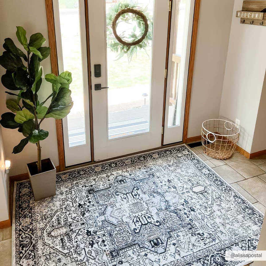 Entryway with a black and light beige Cabacungan Washable Area Rug, a potted plant, and a white door with a wreath. Roomscene-Rectangle
