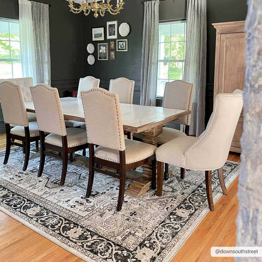 Dining room with a black, gray, and beige Cabacungan Washable Area Rug under a wooden table and upholstered chairs. Roomscene-Rectangle