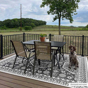 Outdoor patio scene with black table and chairs on a black and white Kingscliff Nordic Rug. Dog sitting on the rug. Roomscene-Rectangle