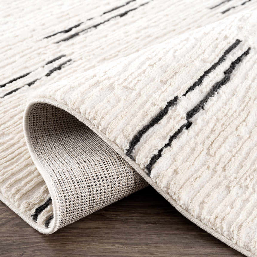 Close-up of the Riad Black Striped White Rug with Tassels, showing the geometric pattern and soft, textured pile. Fold