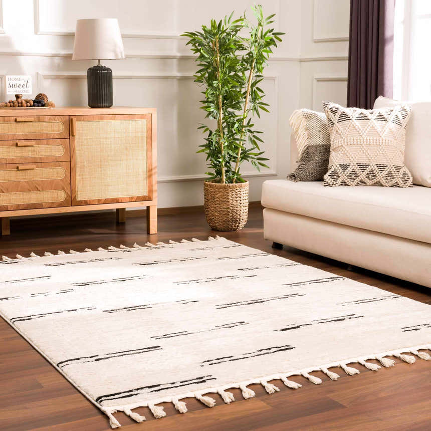 Living room scene with Riad Black Striped White Rug. Beige sofa, wood cabinet, and plant create a cozy, modern space. Roomscene-Rectangle