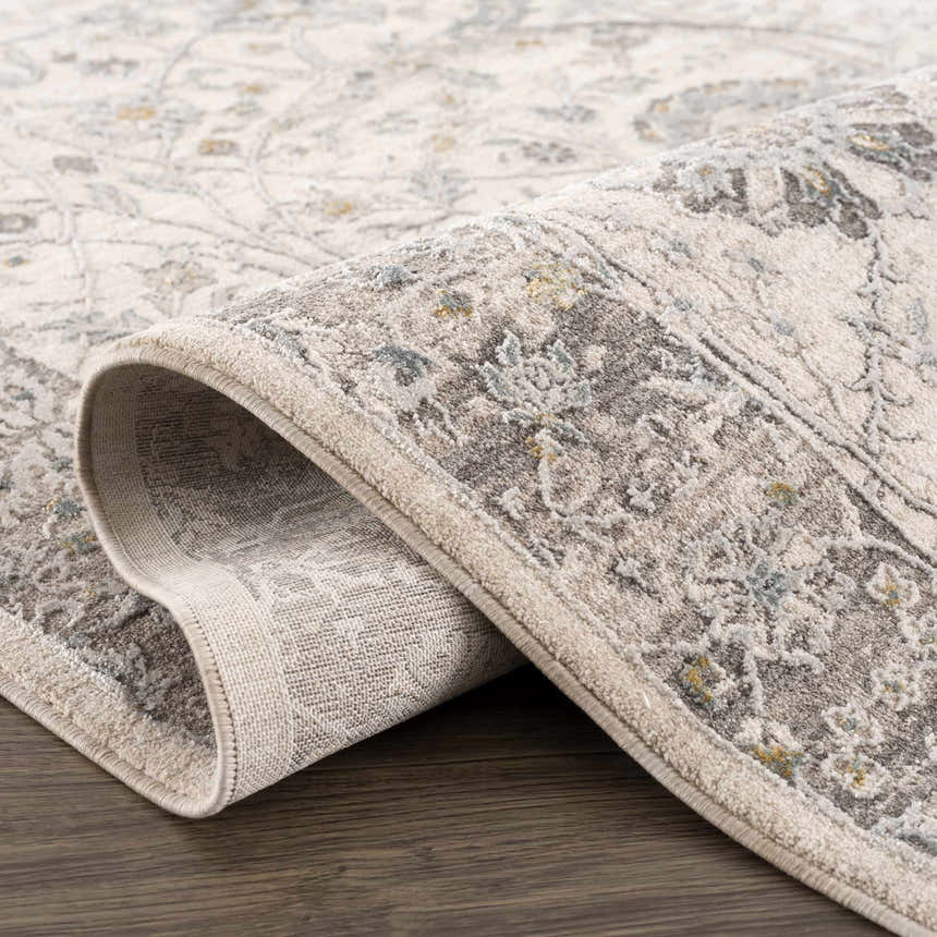 Close-up of the Gauge Cream & Gray Blue Rug showing its traditional floral pattern and soft, textured weave. Fold
