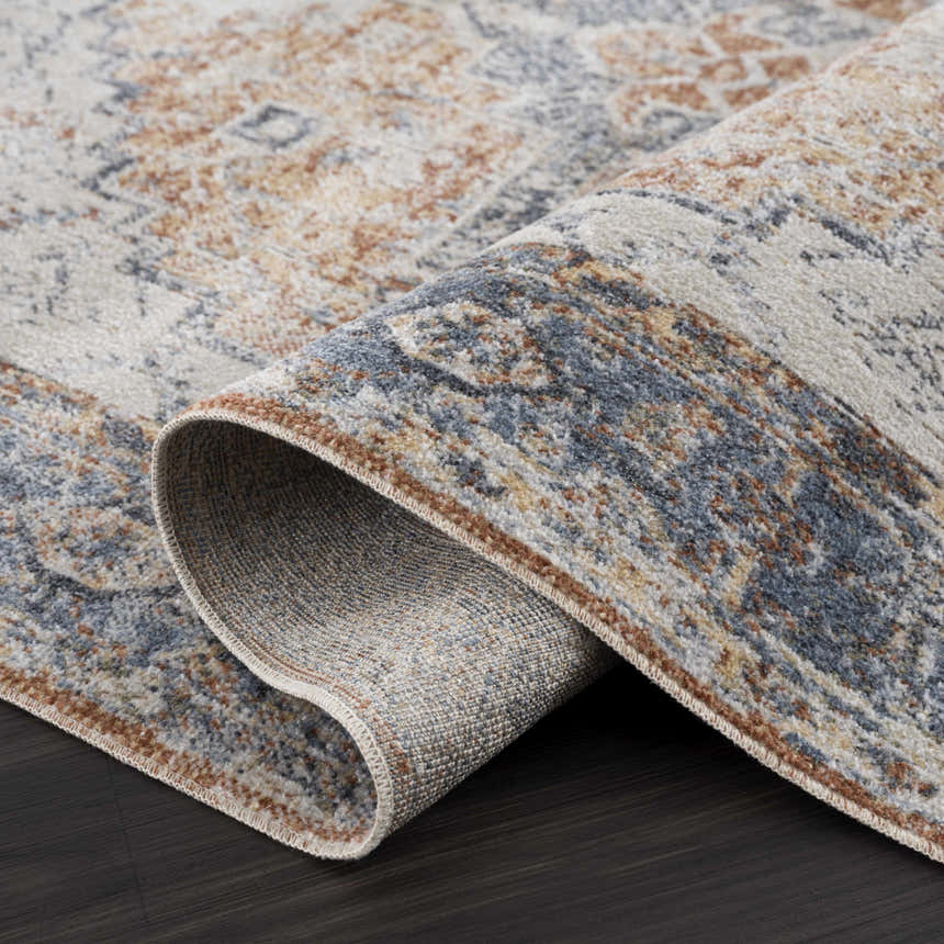 Close-up of the Blue Orange Hera Washable area rug showing its traditional vintage pattern and soft texture. Fold