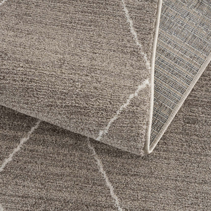 Close-up of Kami Area Rug showing dark beige pile, ivory geometric design, and woven backing. Fold