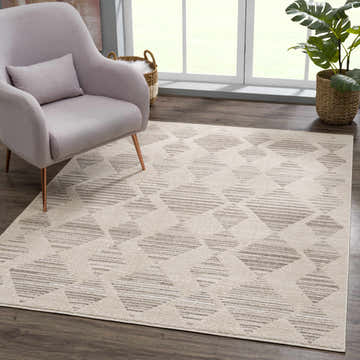 Living room scene with beige Nalu Area Rug, lilac armchair, wood floors, and natural light. Roomscene-Rectangle