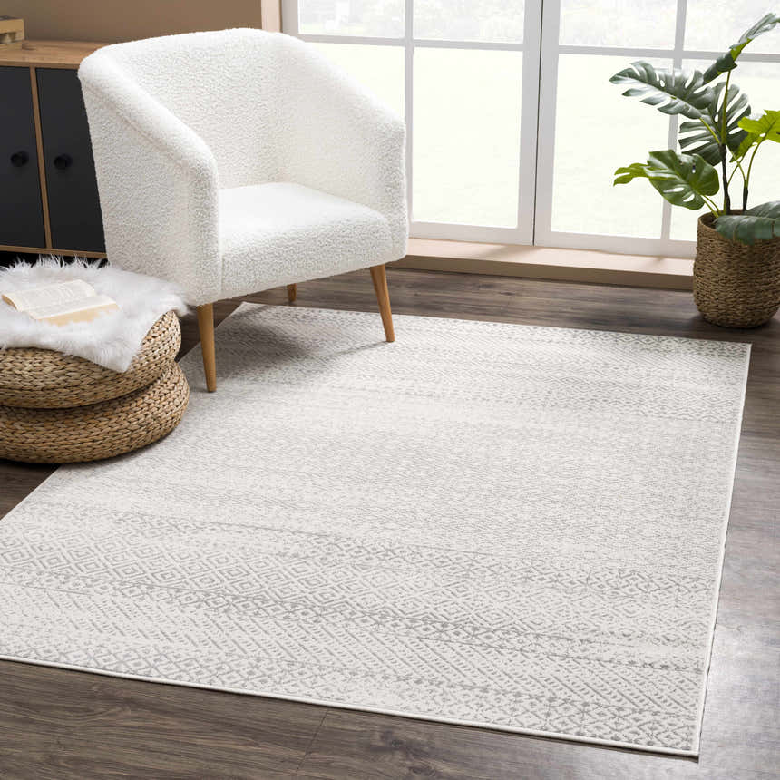 Living room scene with a Tigri Aztec Ivory & Gray rug, white sherpa chair, woven ottoman, and dark wood floors. Roomscene-Rectangle