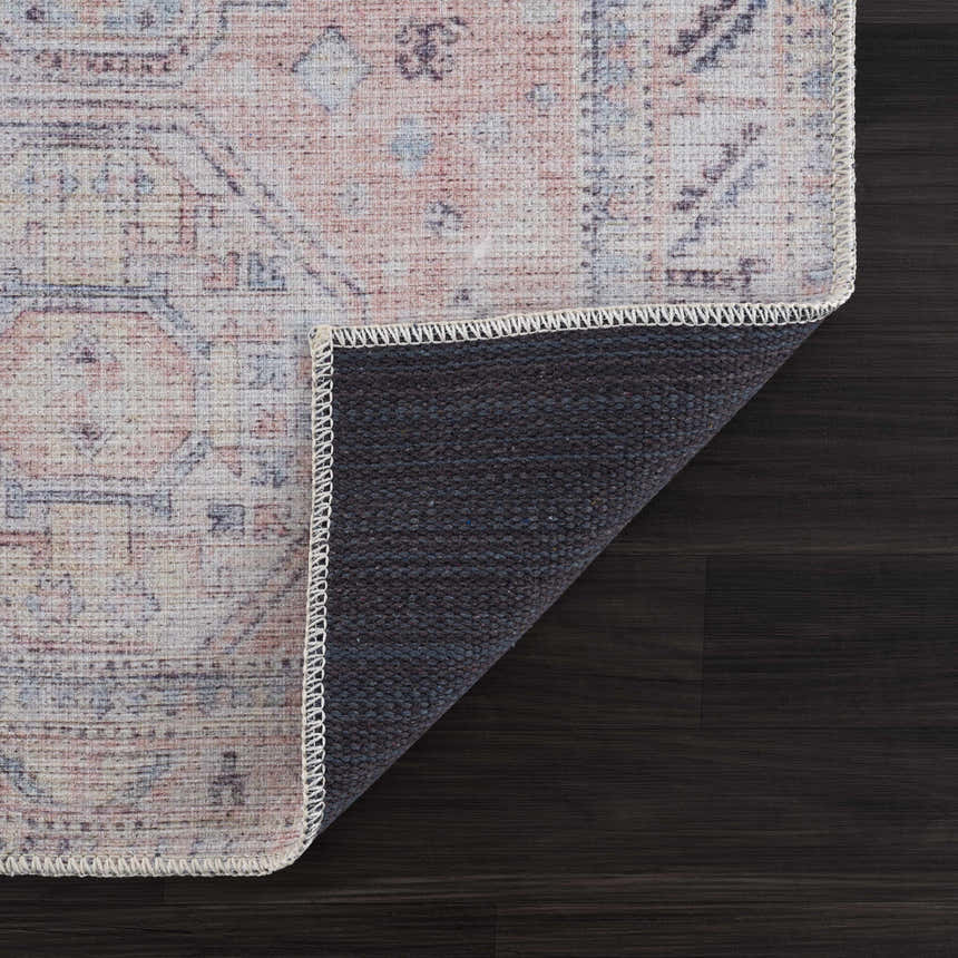 Close-up of Morcott Peach Washable Area Rug showing the traditional pattern, peach, ivory, blue tones, and non-slip backing. Fold
