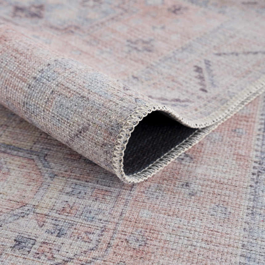 Close-up of the Morcott Peach Washable Area Rug showing its chenille-polyester texture and traditional design. Fold