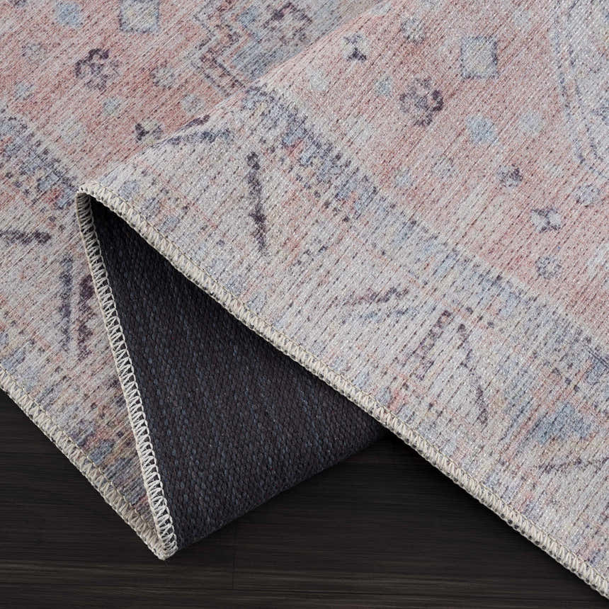 Close-up of the Morcott Peach Washable Area Rug showing its chenille texture, oriental pattern, and colors: peach, ivory, and pale blue. Fold