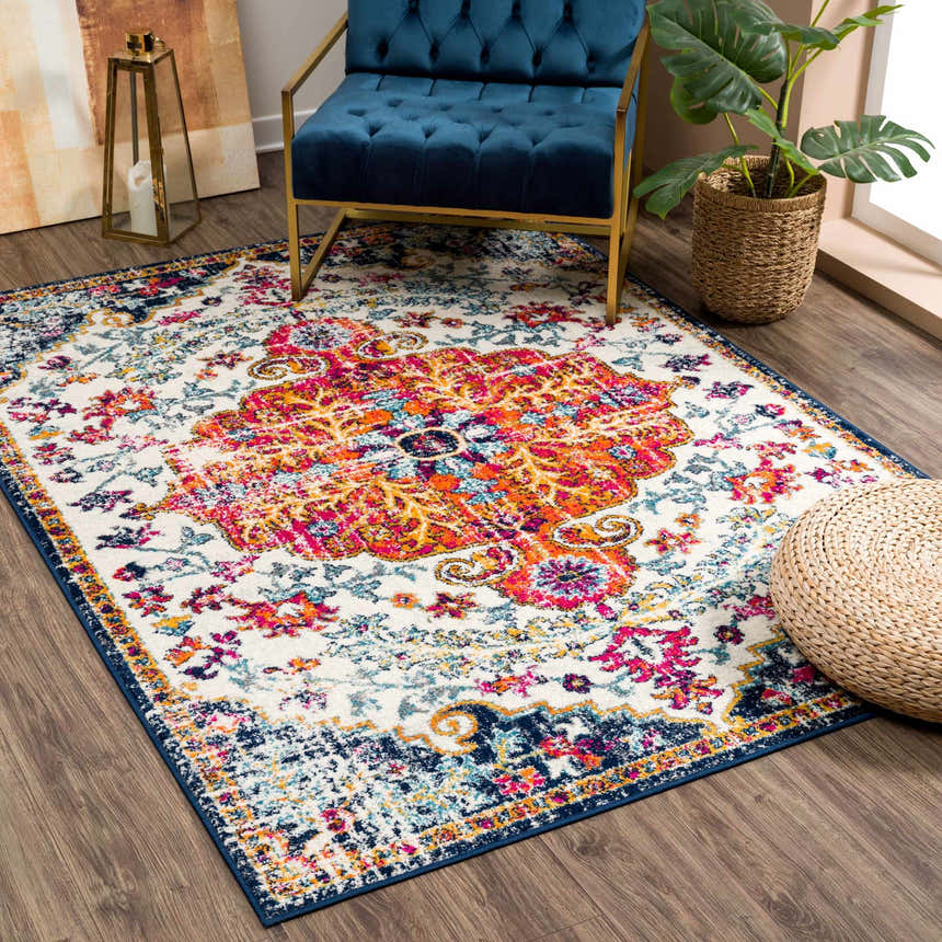 Living room scene with Bodrum Lite Colorful Rug, blue velvet chair, and woven pouf. Roomscene-Rectangle