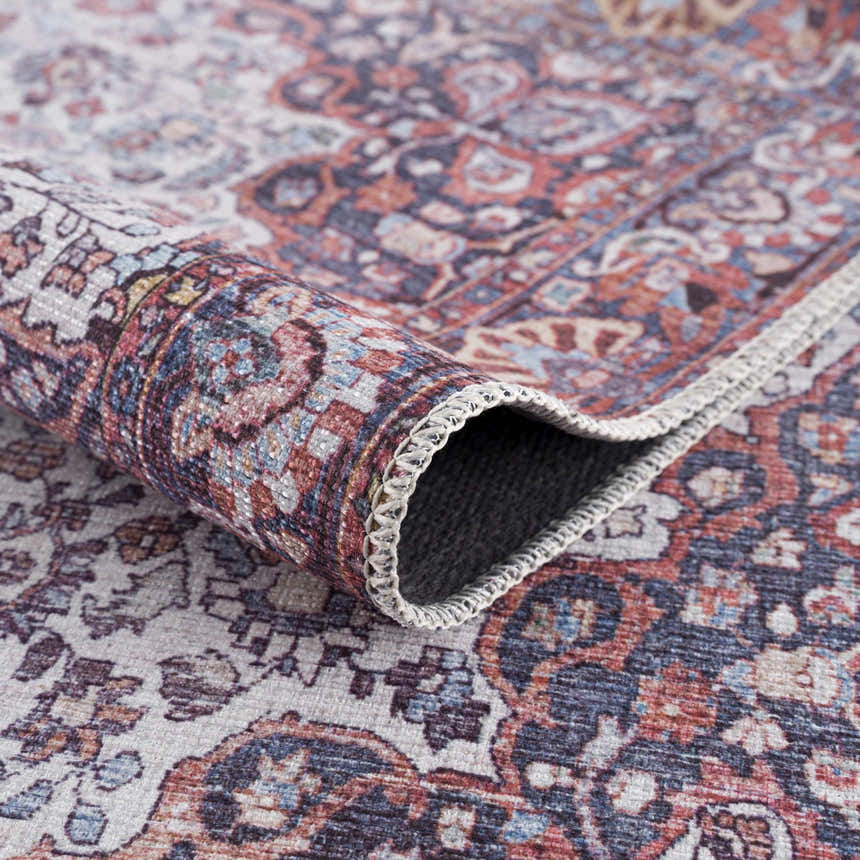 Close-up of the Red Cael Tumble Washable Rug showing the oriental, Persian-style pattern and texture. Fold
