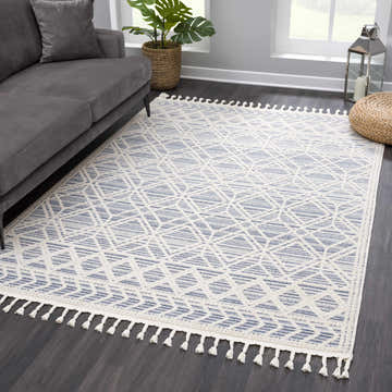 Living room scene with gray sofa and Magnolia Blue 2302 Area Rug. The rug has a cream and blue geometric pattern with tassels. Roomscene-Rectangle