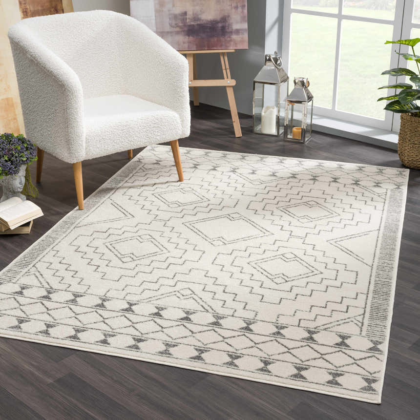 Living room scene with a white armchair and Ivory Tribal Carpet KMRSH-4614. The rug has a gray geometric pattern. Roomscene-Rectangle