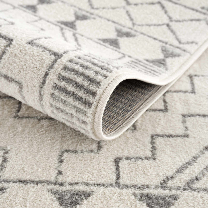 Close-up of the Ivory Tribal Carpet KMRSH-4614, showing the gray geometric pattern and soft, textured polypropylene pile. Fold