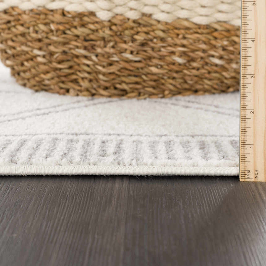 Close-up of the Ivory Tribal KMRSH-4614 rug showing texture, pile height, and gray geometric pattern. Basket and ruler included. Pile