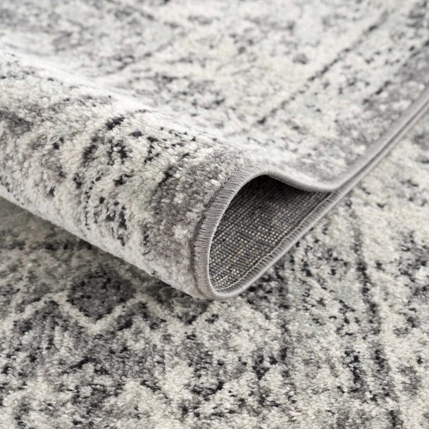 Close up of the Marash KMRSH-4615 area rug. Black, gray, and ivory tones with a subtle, abstract pattern and soft texture. Fold