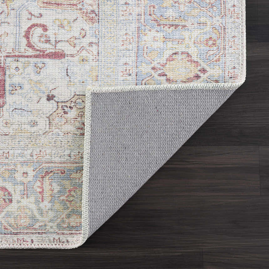 Close-up of the Cream Rust Leeston Washable Rug showing its traditional design, brick red, cream, and light blue colors. Fold