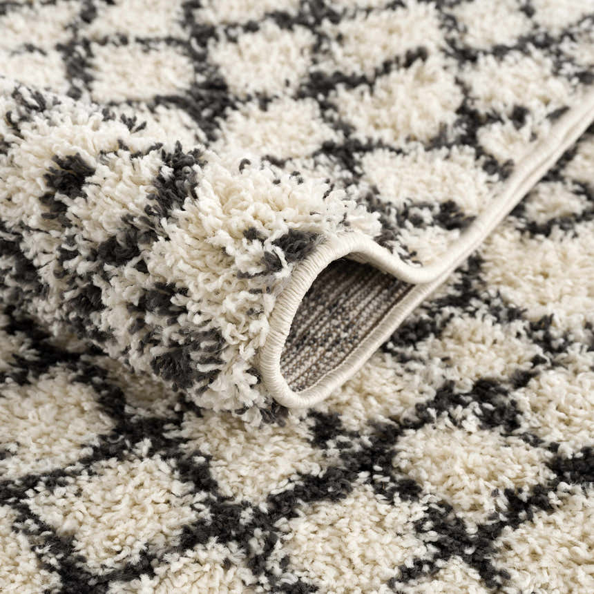 Close-up of the Muni Berber Shag Rug. Charcoal and light beige shag rug with a geometric Moroccan-inspired pattern. Fold