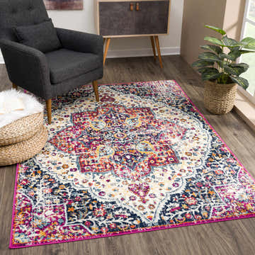 Living room scene with Marash KMRSH-4601 rug in ivory, navy, pink, and purple. Gray chair, wood floors, and plant. Roomscene-Rectangle