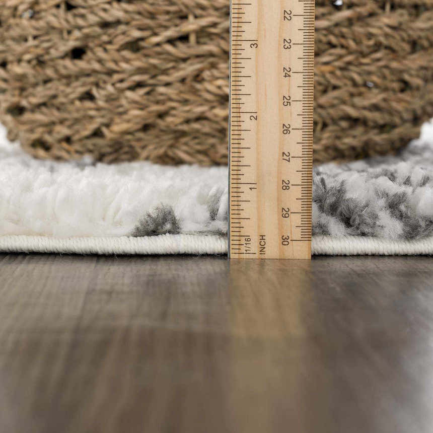 Close-up of the Trunding Plush Area Rug showing its thick pile, charcoal and cream colors, and a ruler for scale. Pile