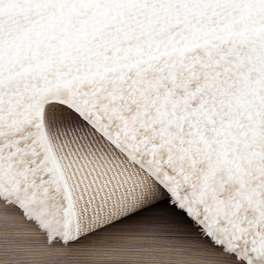 Close-up of the Hauteloom Trunding Plush Rug in Light Beige, showing its fluffy texture and woven backing. Fold