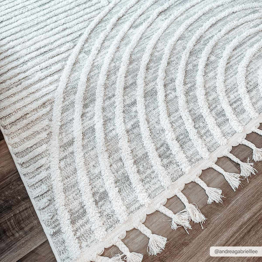 Close-up of the Dauin 3D Rainbow Area Rug showing the gray and cream geometric pattern and tassel fringe detail. Roomscene-Rectangle