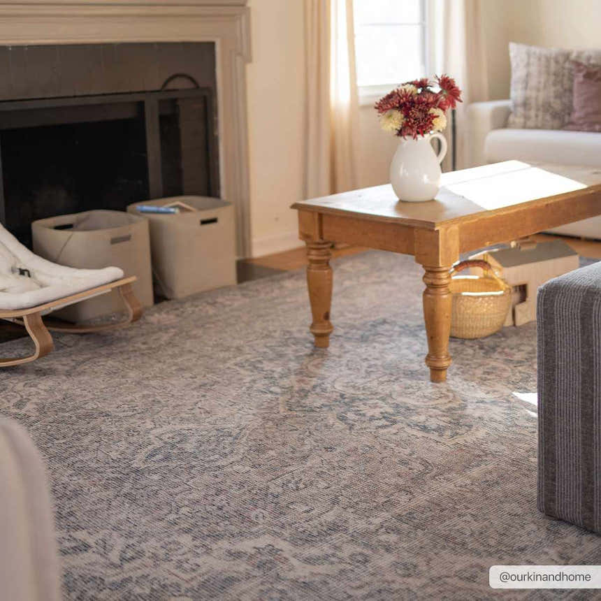 Living room scene with a Greenpoint Dusty Blue Washable Rug, wood coffee table, fireplace, and neutral tones. Roomscene-Rectangle