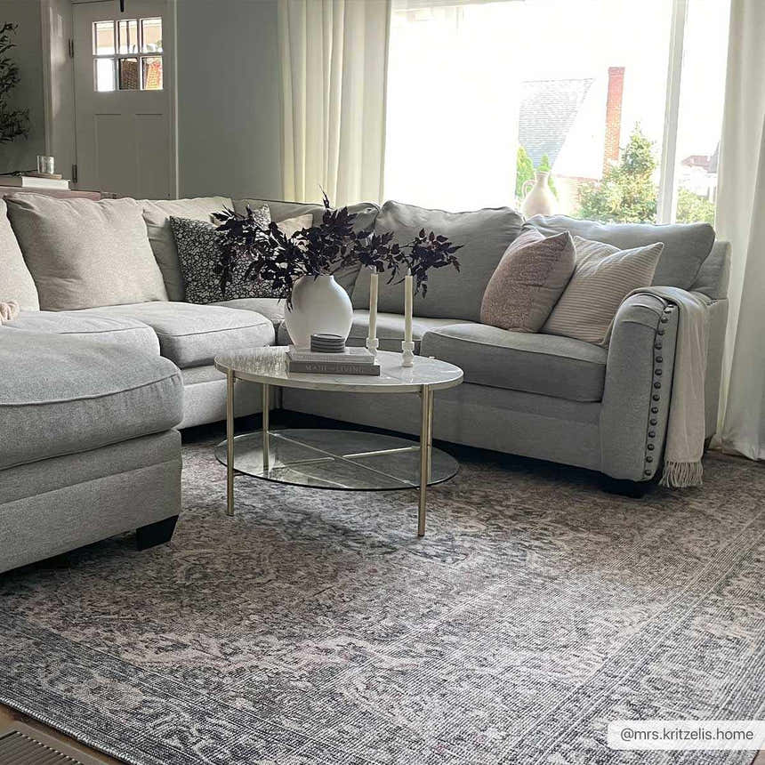 Living room scene with gray sectional, marble table, and Greenpoint Dusty Blue Washable Rug with beige, black, and red tones. Roomscene-Rectangle
