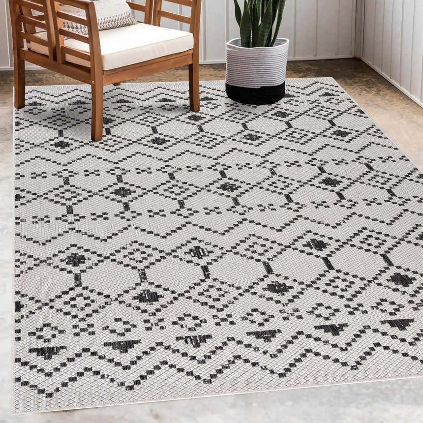 Room scene with Haynesville Moroccan Design Pixel Rug, wood chair, and potted plant. Black and white bohemian style. Roomscene-Rectangle