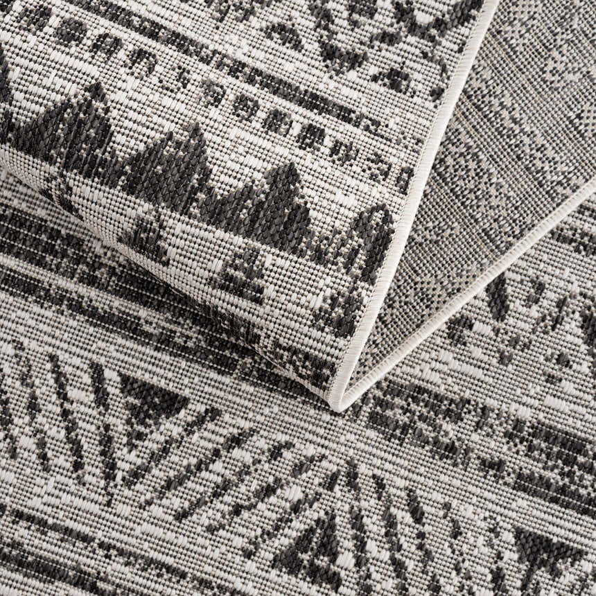Close-up of the Catrine Indoor & Outdoor Rug showing its black, charcoal, and off-white bohemian pattern. Fold