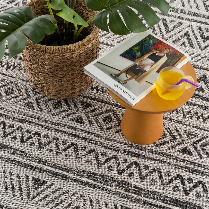 Close-up of the Catrine Indoor & Outdoor Rug showing its black, charcoal, and off-white bohemian pattern and woven texture. Styleshot