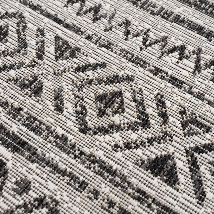 Close-up of the machine woven Catrine Indoor & Outdoor Rug. Black, charcoal, and off-white bohemian pattern. Texture