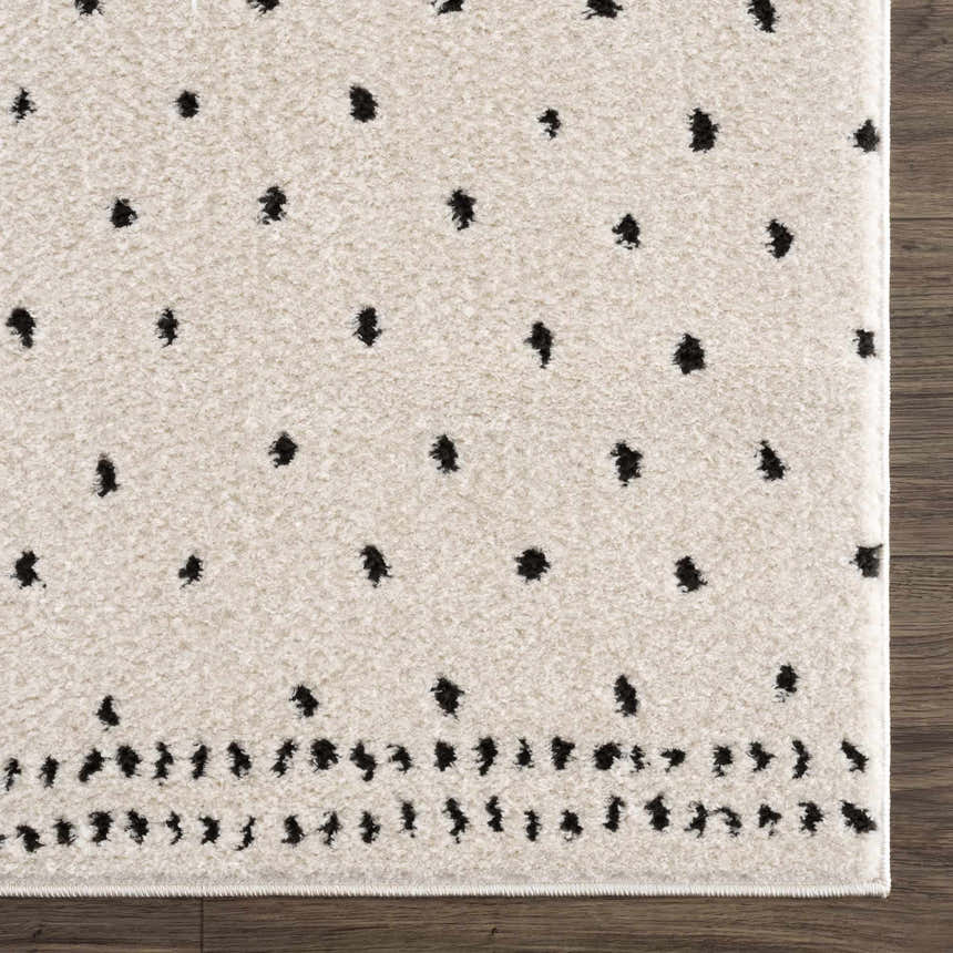 Close-up of the Julie Area Rug, showcasing its beige and black polka dot pattern and soft, textured weave. Swatch