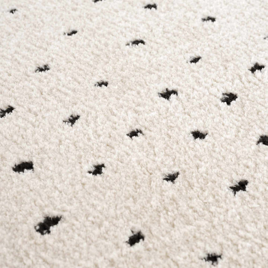 Close-up of the Julie Area Rug showing its beige shag texture and black polka dot pattern. Texture