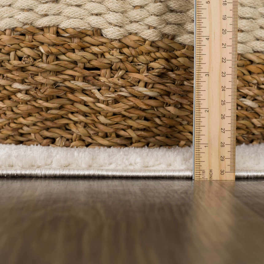 Close-up of the Keats Area Rug showing the ivory pile height next to a ruler, with beige and brown woven texture. Pile